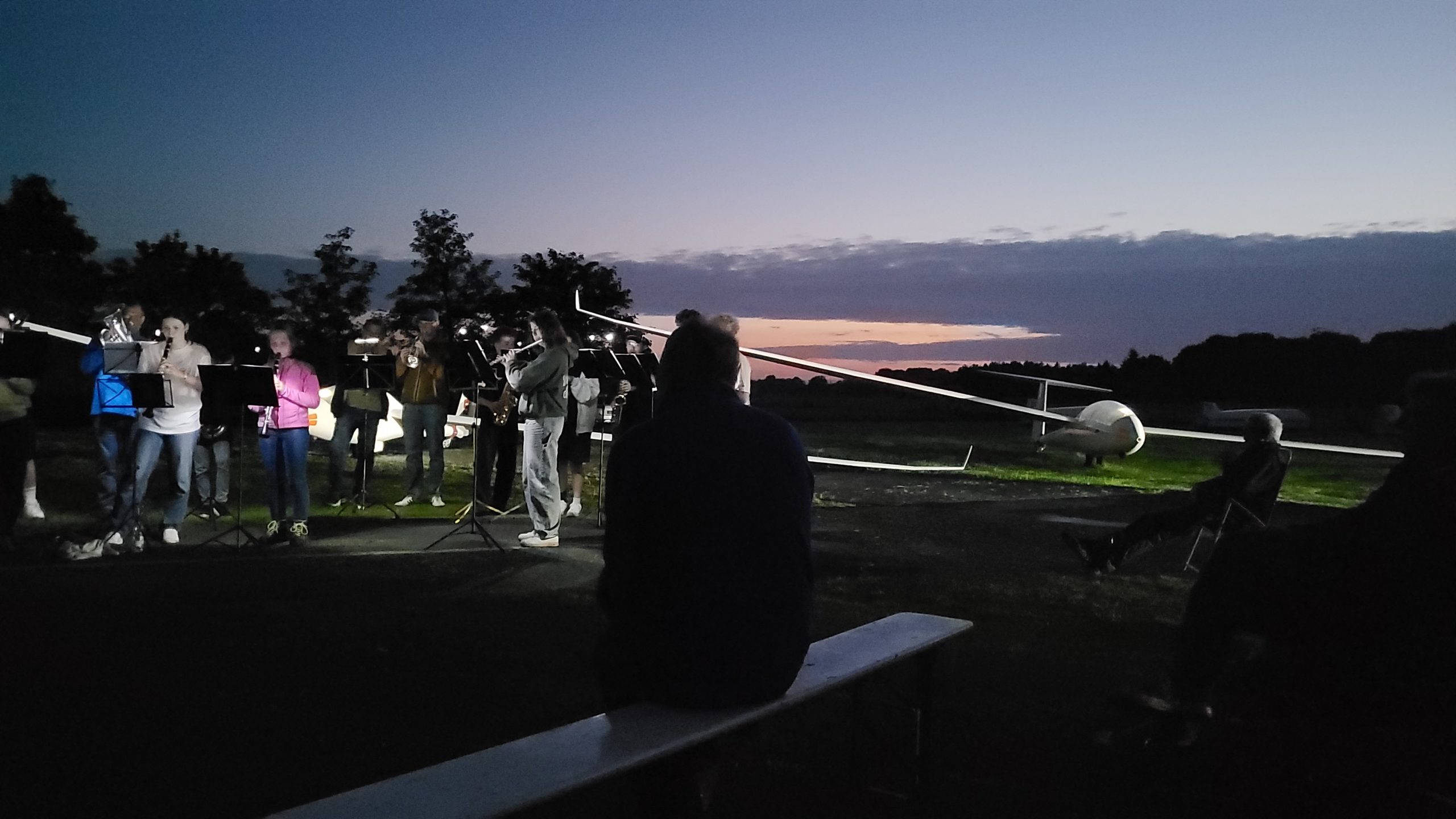 Konzert am Abend vor einem beleuchteten Segelflugzeug